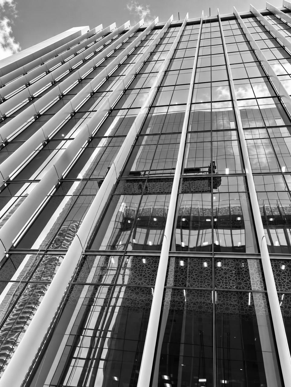 Looking up the tower facade — glass and steel fins against the sky